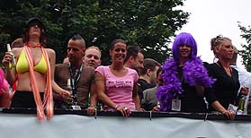 sexy Frau mit Mixgetränk und geiler Figur, Frau mit Shirt: Wer leckt wird auch geblasen, Frau mit lilafarbenem Fellimitat und lila Haaren